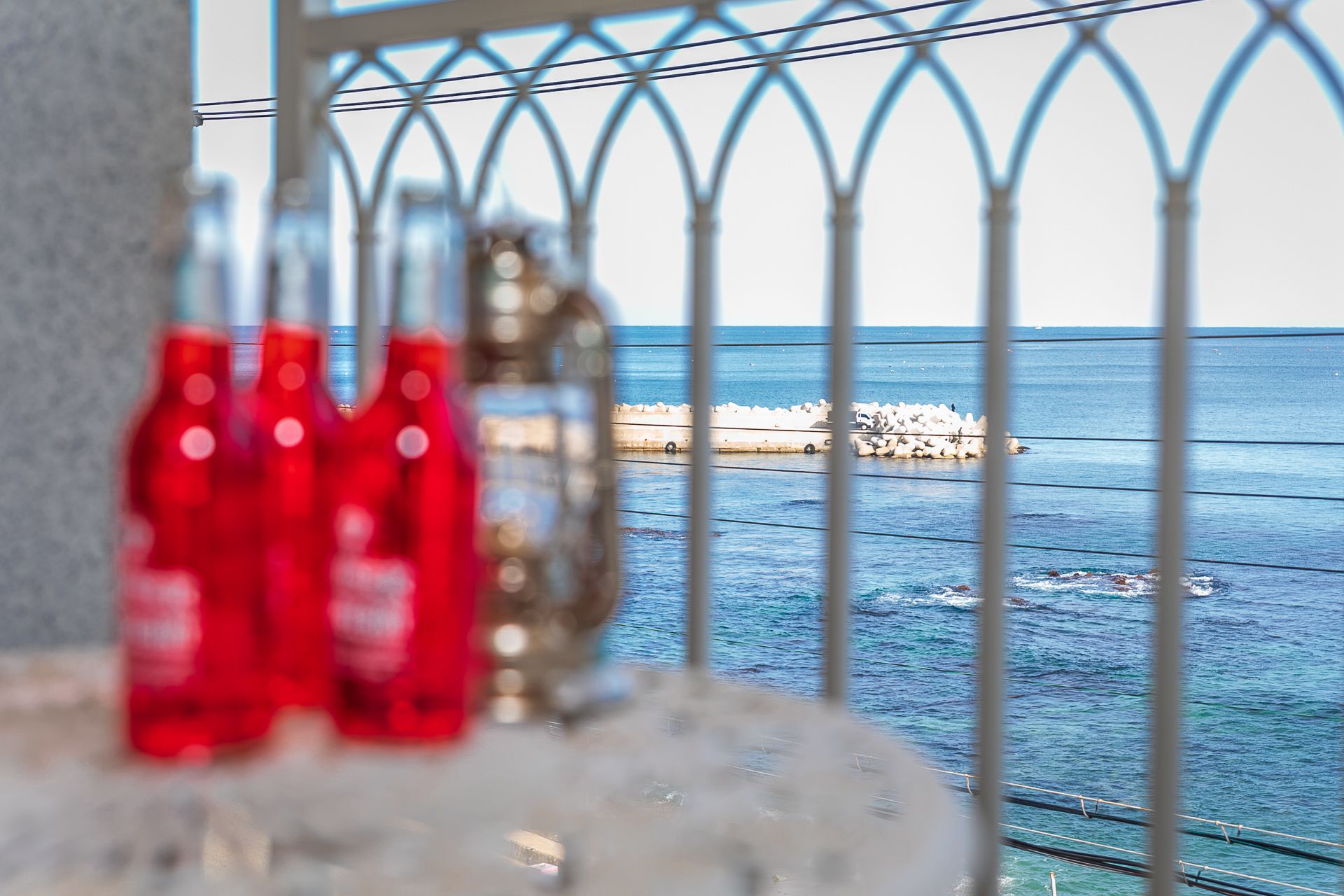 A view through a metal railing with bottles on a table in the foreground.