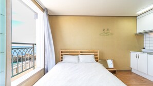 Un dormitorio con cama, ventana y vista a la playa, además de un kitchenette.