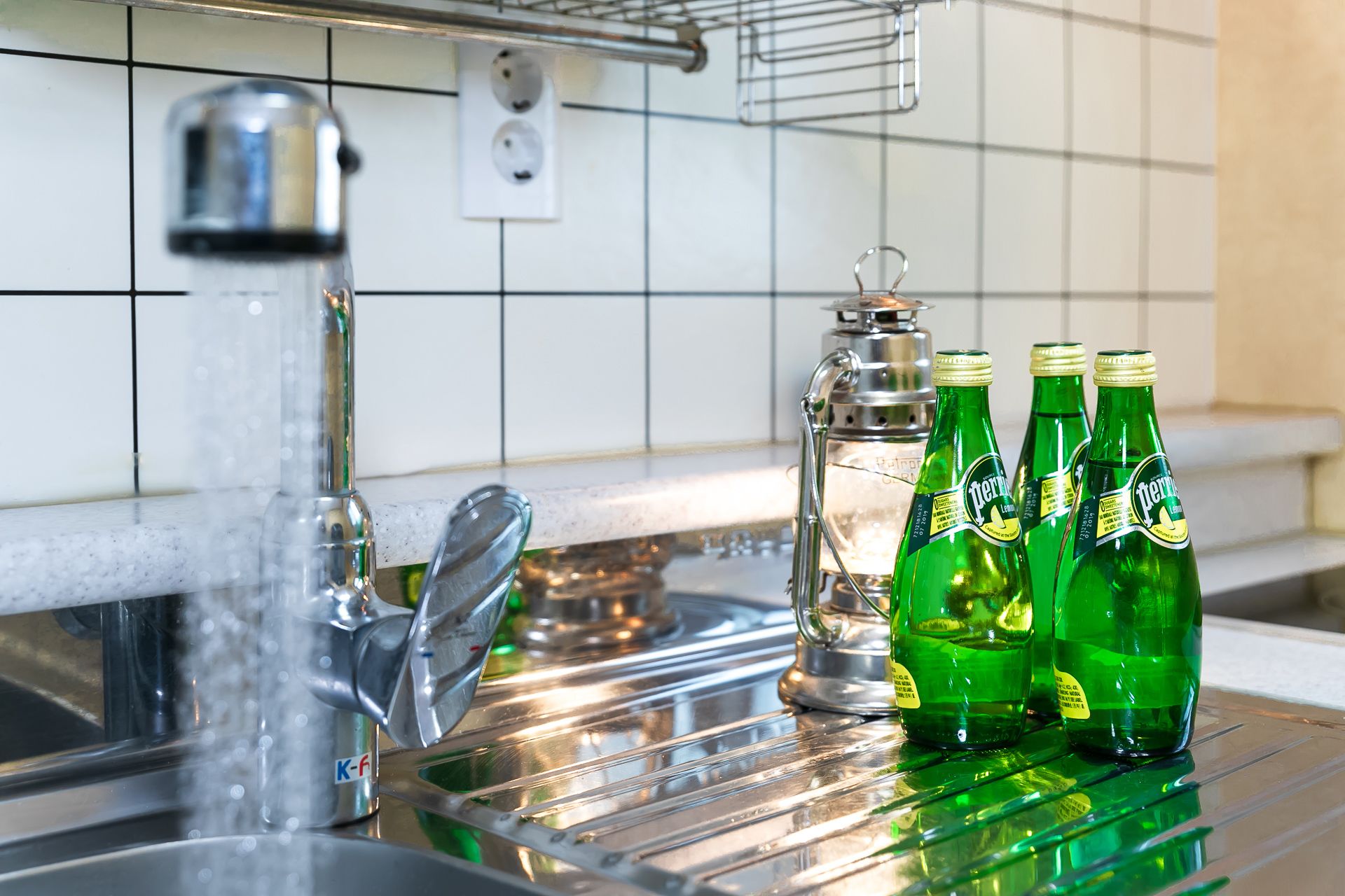 Eine Spüle mit einem Metallarmaturen, eine Glasflasche und drei grüne Flaschen mit Etiketten.