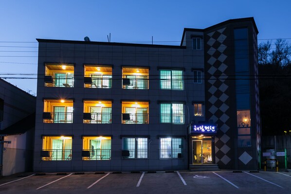 A multi-story hotel with a modern design, featuring balconies, large windows, and a parking lot in front. - Haelim Pension (Yeongdeok)