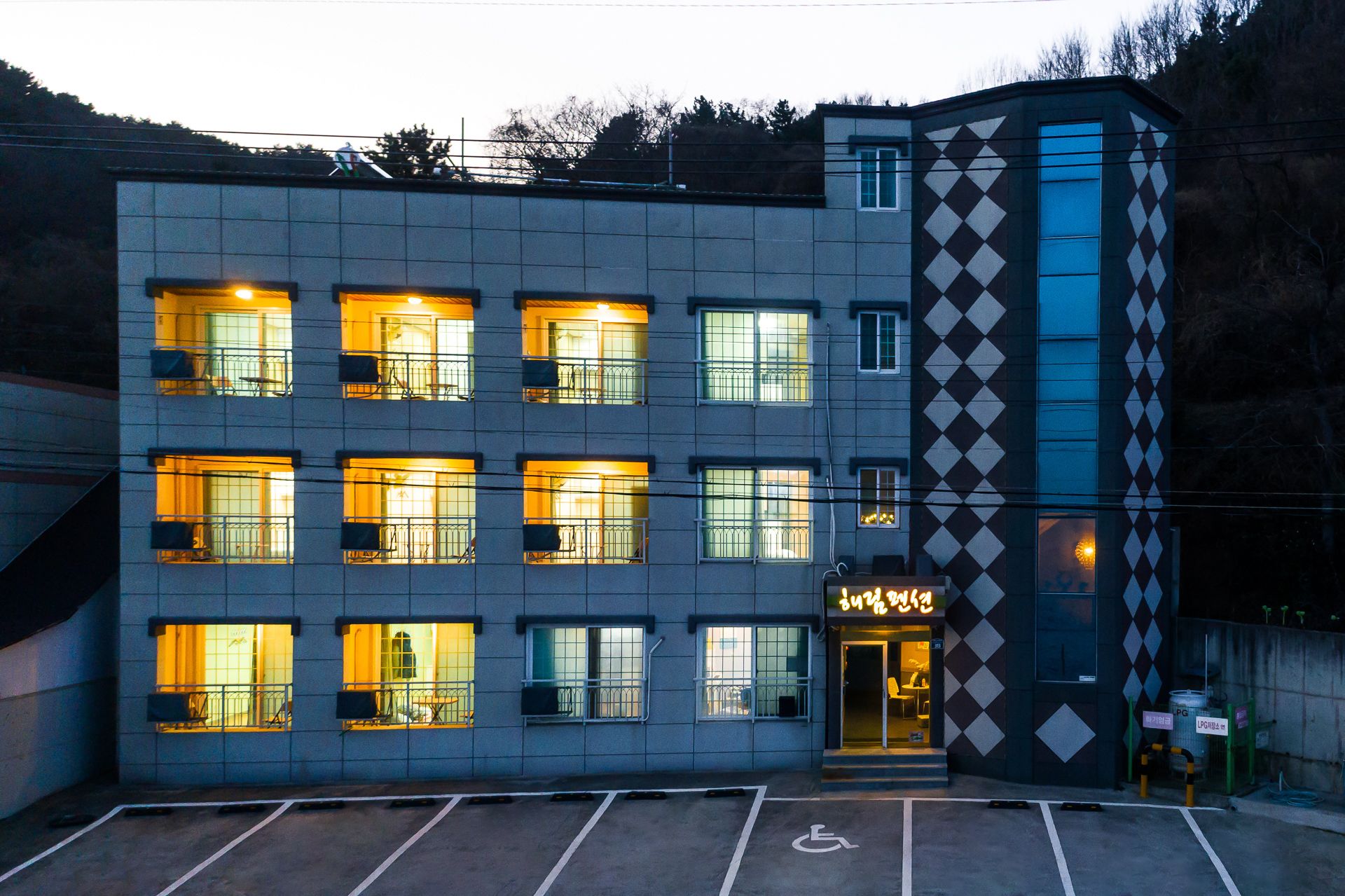 A multi-story building with a distinctive diamond-patterned facade, multiple illuminated windows, and a wheelchair-accessible entrance.