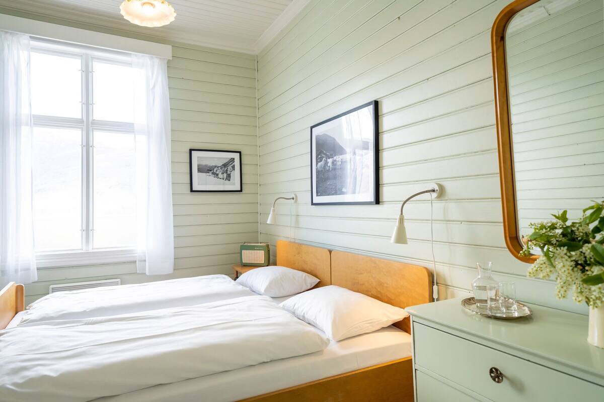 A room with a bed, a dresser, a mirror, and two framed pictures on the wall.