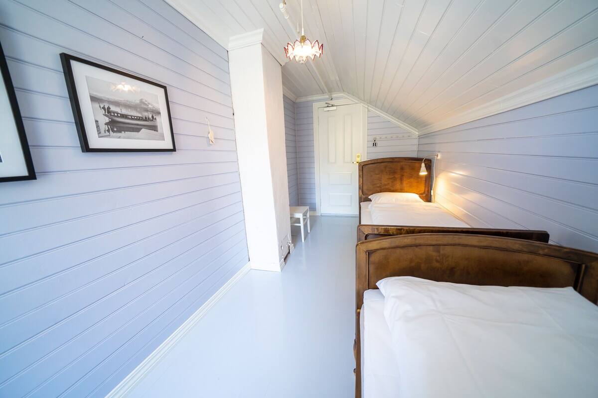 A room with two beds, a wooden headboard, a framed picture on the wall, and a chandelier.