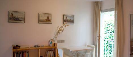 A room with a white desk, two chairs, a bookshelf, and three framed pictures on the wall.