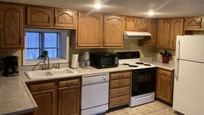 A kitchen with wooden cabinets, a white refrigerator, a stove, a microwave, and a dishwasher.