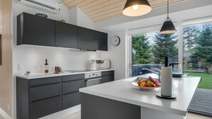 Una cocina moderna con armarios oscuros, una isla central, un reloj y vistas al exterior.