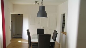 Un espace repas comprenant une table et des chaises, un luminaire suspendu et un plancher en bois.