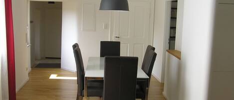 Un espace repas comprenant une table et des chaises, un luminaire suspendu et un plancher en bois.