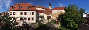 Un edificio europeo tradicional con tejado de tejas rojas, una pequeña torre y un jardín con un columpio.
