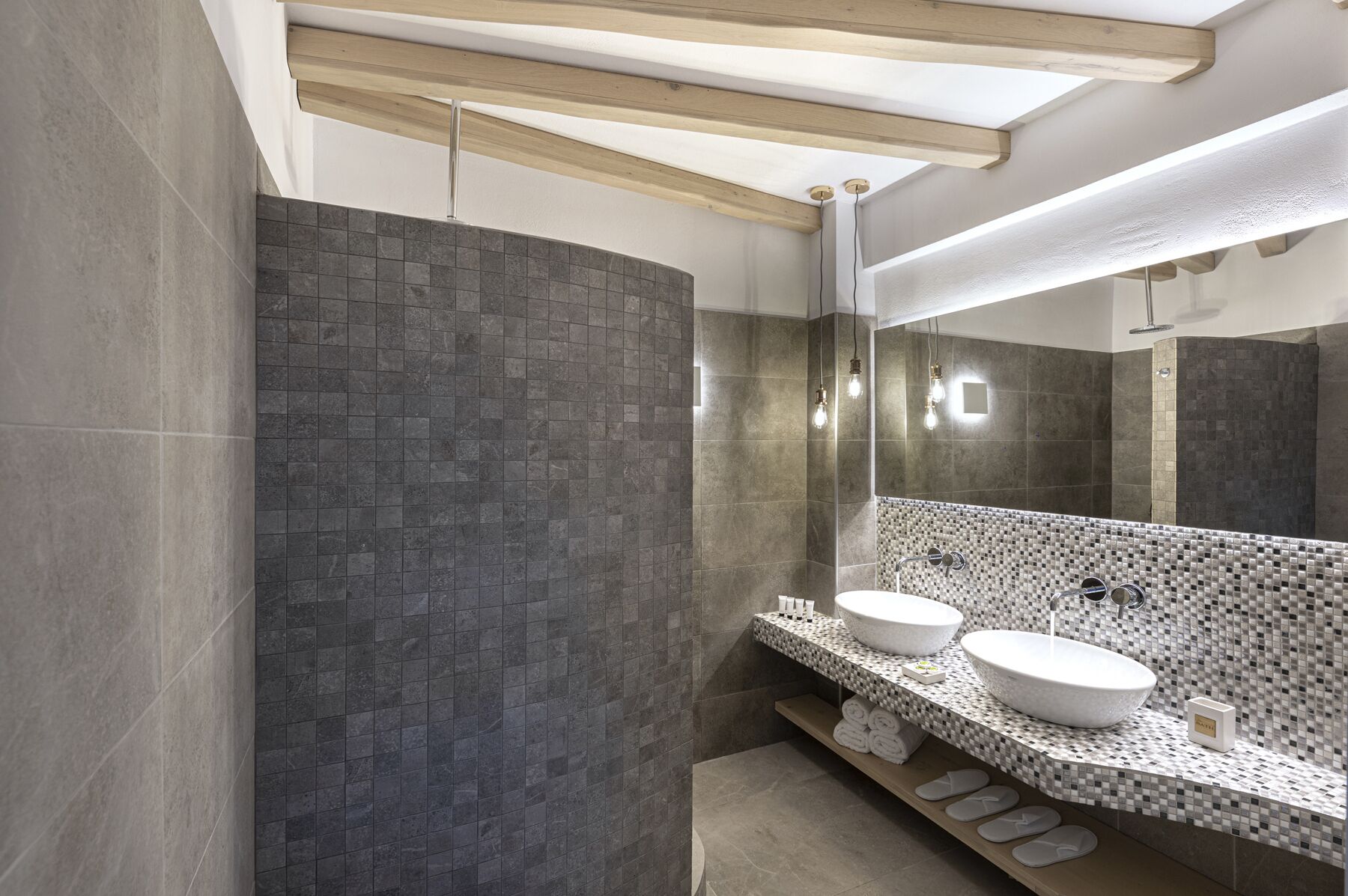 A modern bathroom with two sinks, a large mirror, and a tiled shower area.