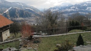 Eine Berglandschaft mit Blick auf ein Tal und ein Gebäude mit rotem Dach.
