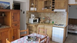 Eine kleine Küche mit Holzschränken, einer Mikrowelle, einer Kaffeemaschine und einem kleinen Kühlschrank.