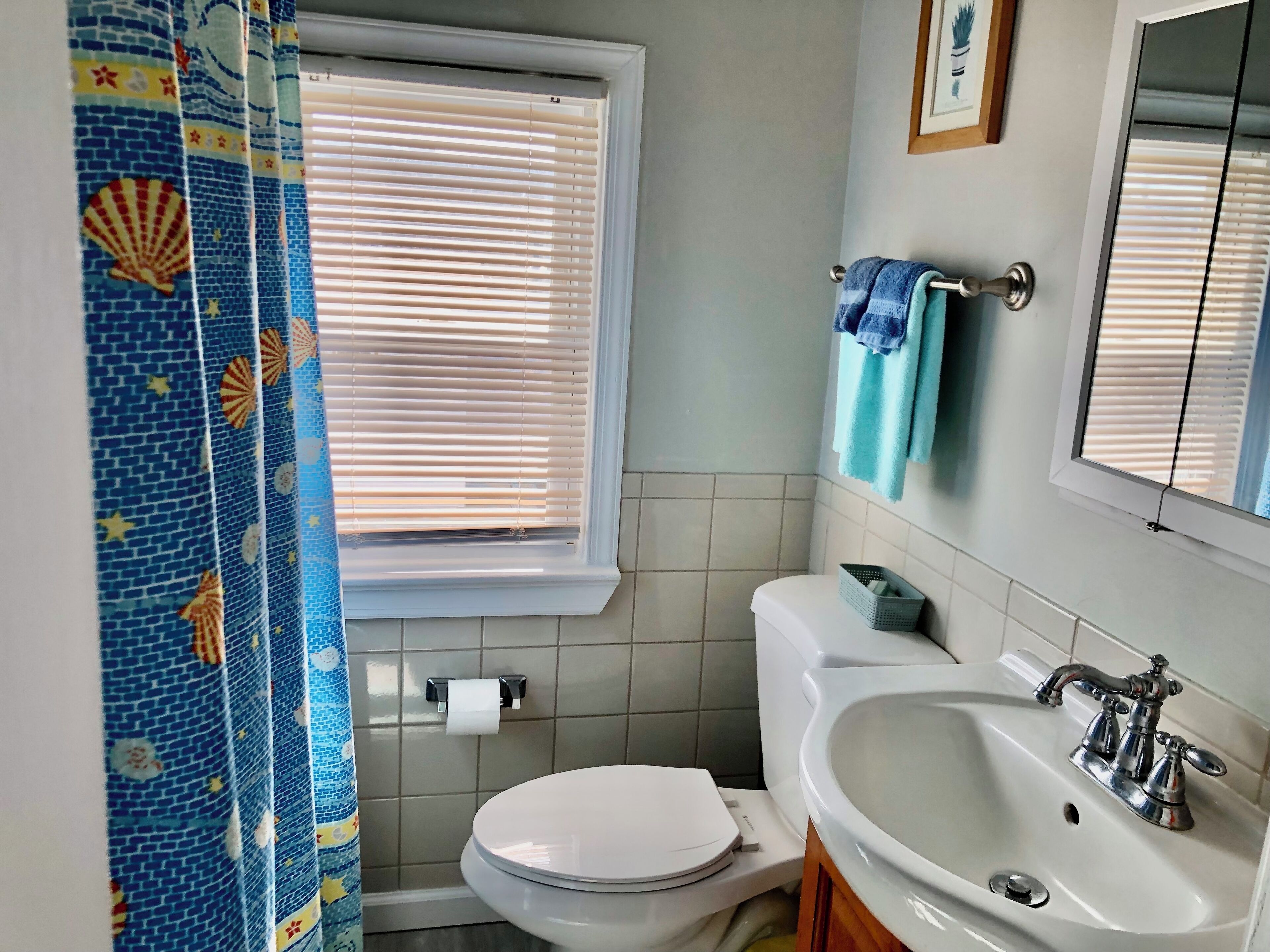 A bathroom with a toilet, sink, and window with blinds.