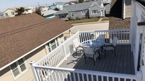 A balcony with a table and chairs, surrounded by a white railing. - BRIGANTINE TOP LOCATION! WALK TO BEACH, EATERIES. 12 NOON CHECKOUT. DOGS OK (Brigantine)