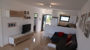 A modern living space with a TV, sofa, dining table, and kitchen area. - Top floor apartment with amazing ocean views  (Costa Teguise)