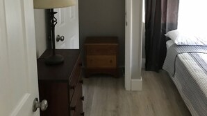 Una camera da letto con un letto, un comodino con lampada, un armadio e un piccolo scrigno di legno.