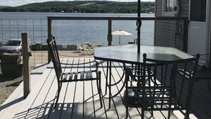 Una terrazza con tavolo e sedie, un ombrellone e vista su un lago e delle colline.