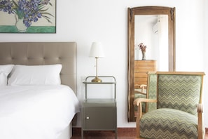 A hotel room with a bed, a nightstand with a lamp, a mirror, a dresser, and a chair. - Agradable apartamento. Congresos- Centro (Granada)