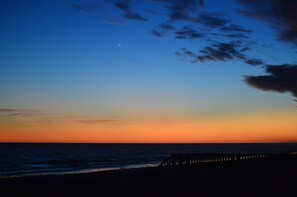 Una puesta de sol sobre el océano con un muelle de madera que se adentra en el agua.