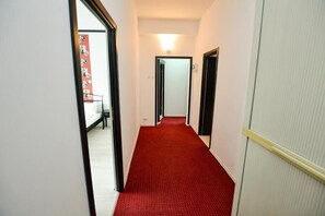 A narrow hallway with a red carpet, white walls, and a door at the end. - Central Class Bucharest (Bucharest)