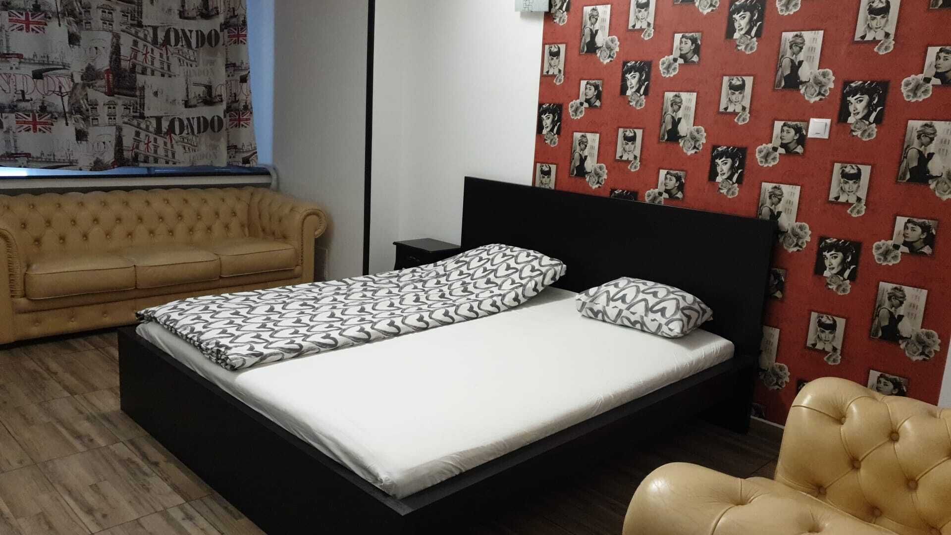 A bedroom with a bed, a sofa, and a wall with pictures.
