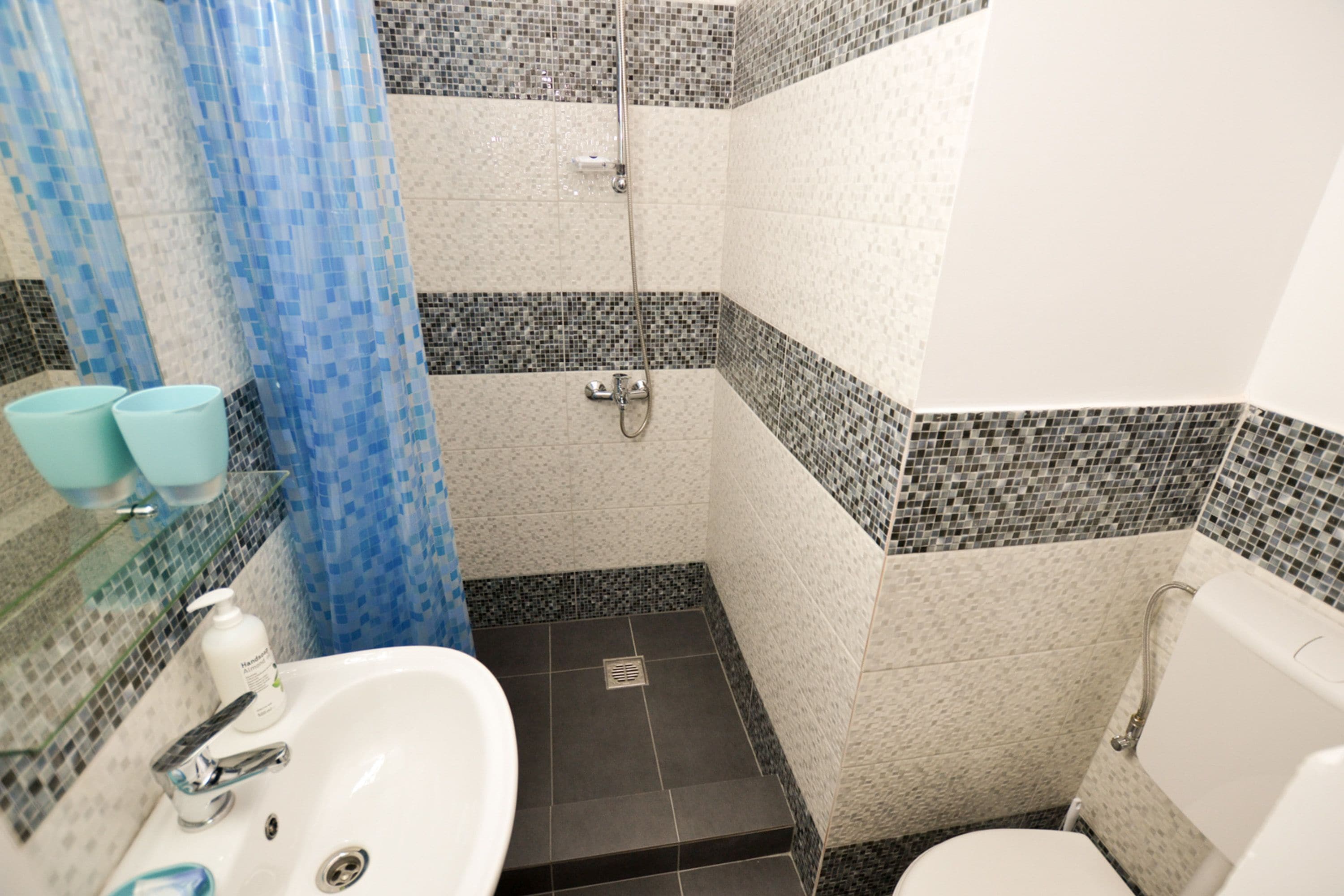 A bathroom with a shower, toilet, sink, and blue shower curtain.