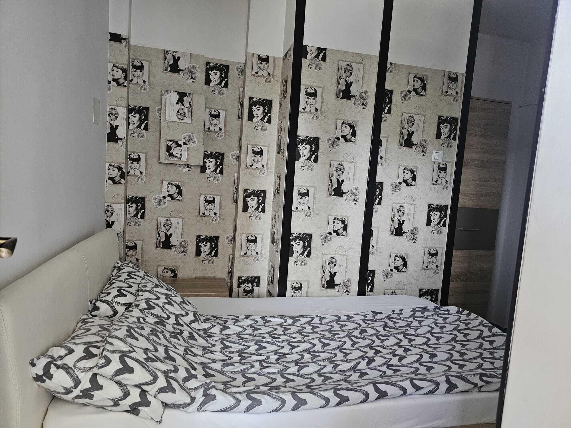Ein Schlafzimmer mit einem Bett, einem Kissen mit Muster und einer Wand mit sich wiederholendem Design.