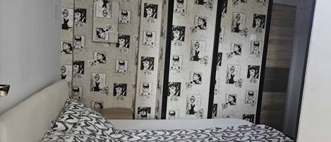 Ein Schlafzimmer mit einem Bett, einem Kissen mit Muster und einer Wand mit sich wiederholendem Design.