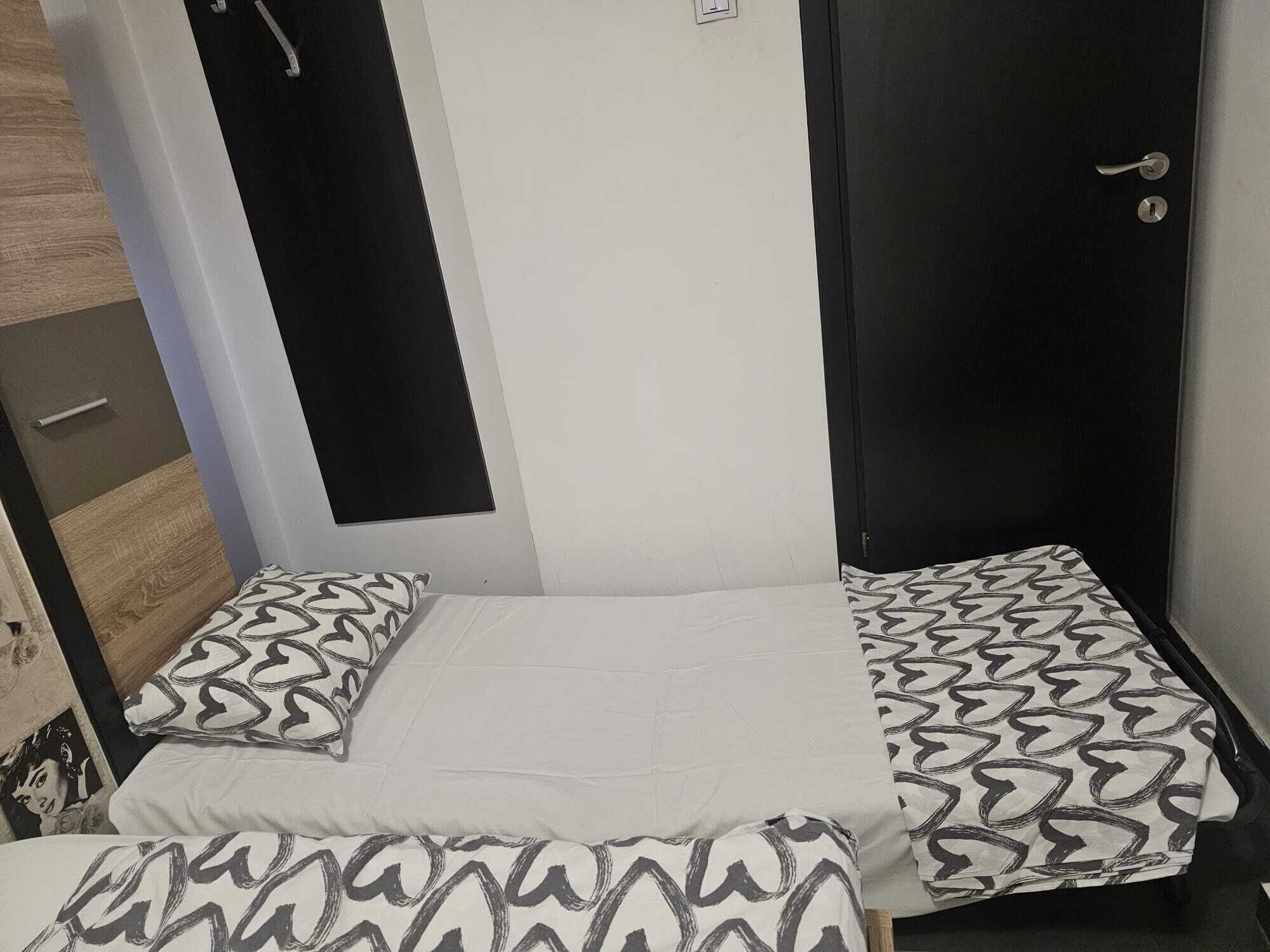 Une pièce comprenant un lit, deux oreillers, une porte et un luminaire fixé au mur.