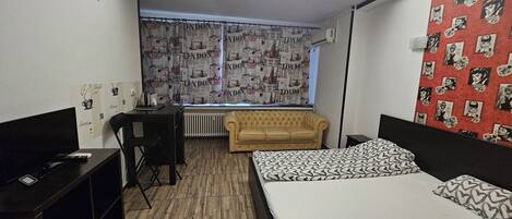 Un dormitorio con cama, sofá, escritorio y radiador.