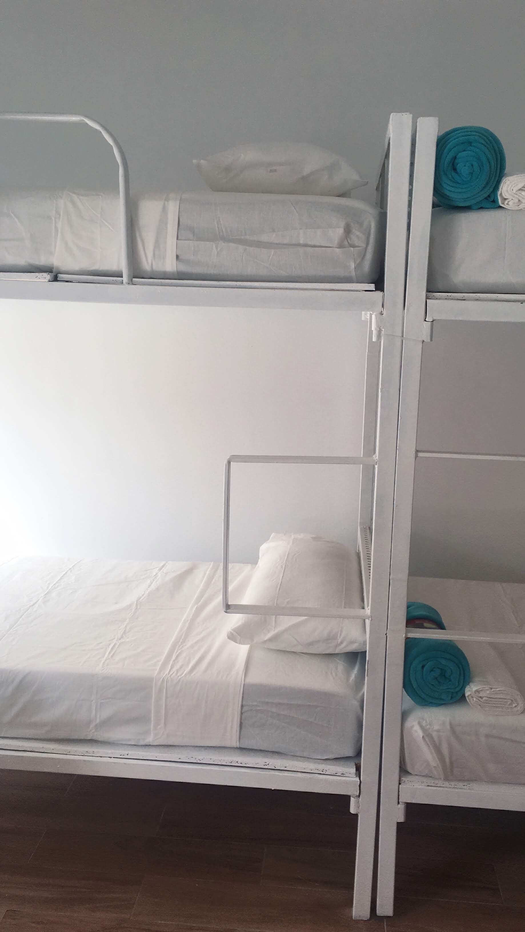 A bunk bed with white bedding and a metal ladder.