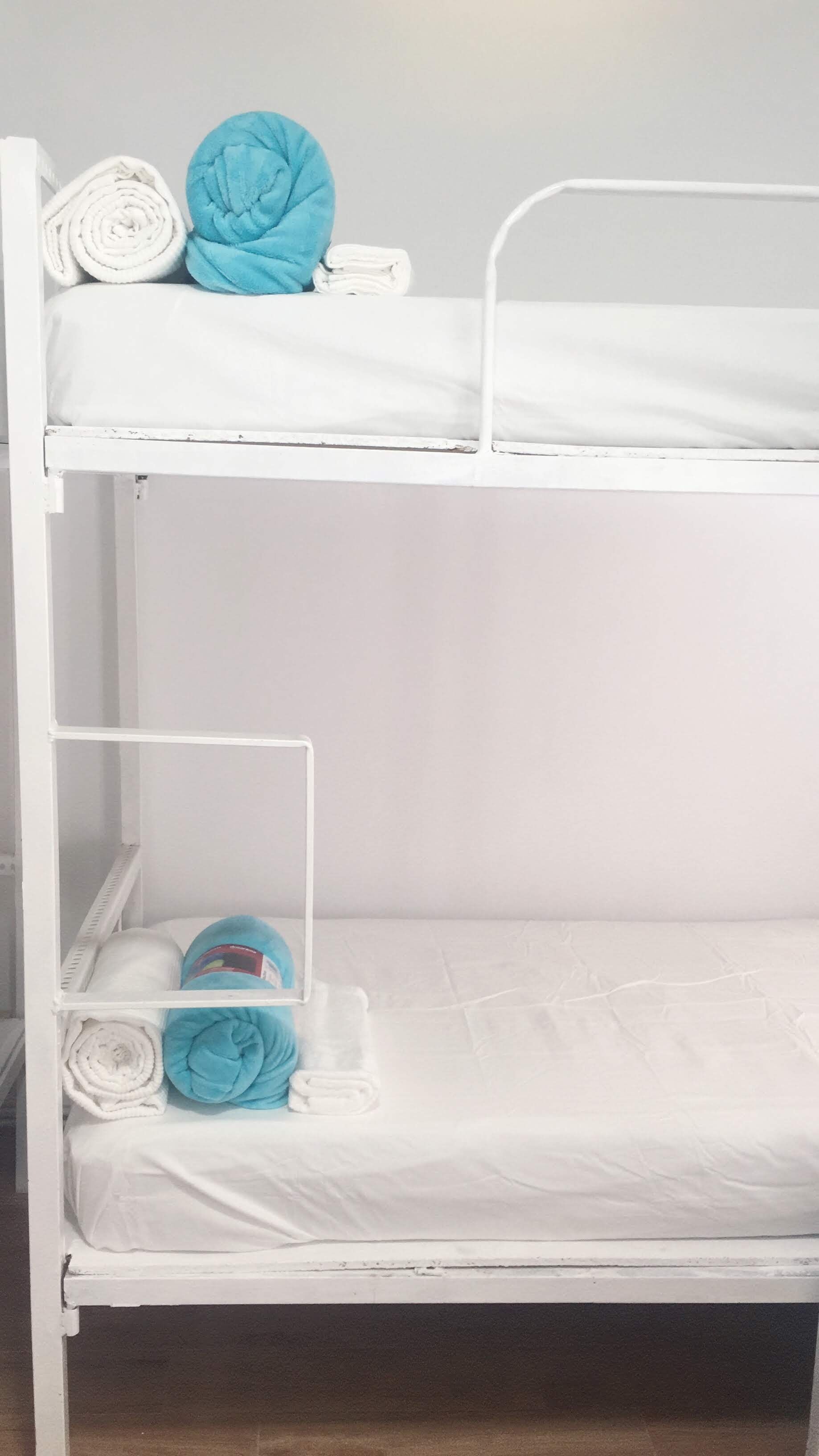 A bunk bed with white bedding and a blue pillow on the top bunk.