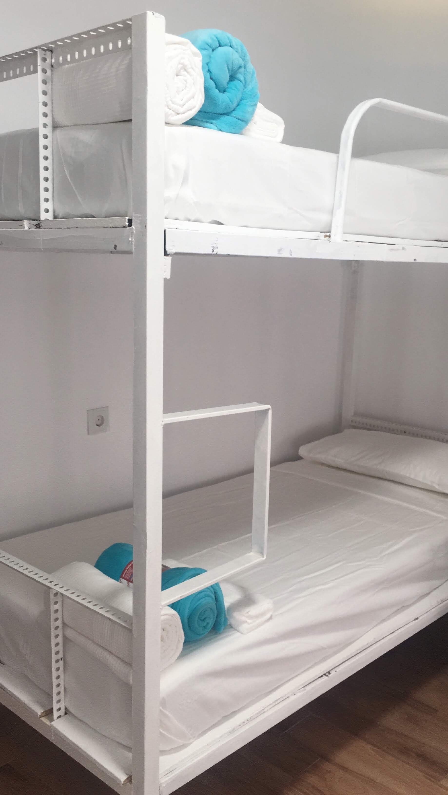 A bunk bed with white bedding and a blue pillow.
