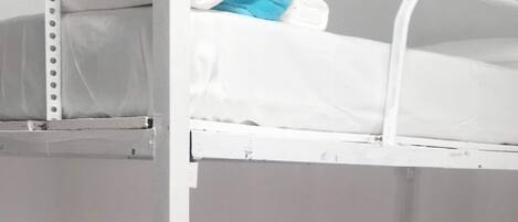 A bunk bed with white bedding and a blue pillow.
