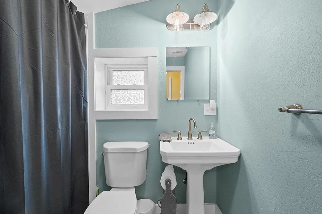 A bathroom with a toilet, sink, and a window with a frosted glass design.