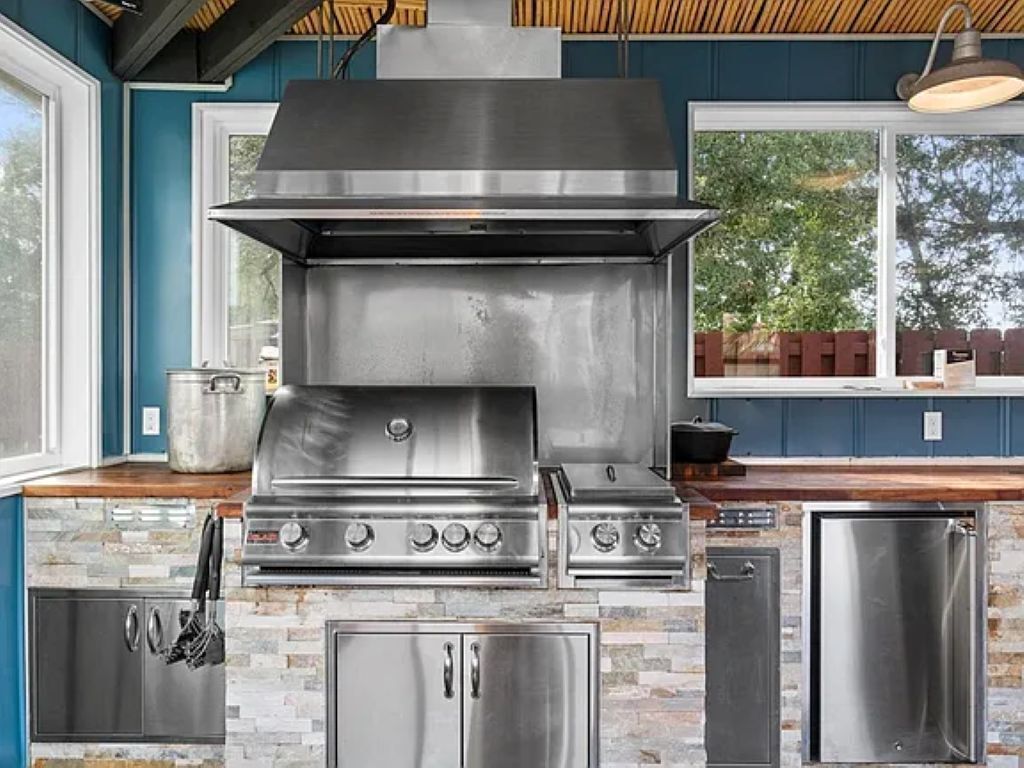 A modern kitchen with a stainless steel range hood, a built-in oven, and a refrigerator.