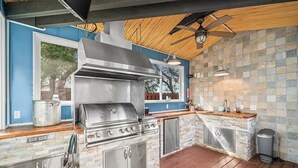 An outdoor kitchen with a stainless steel grill, a wooden ceiling, and stone tile walls. - Great Views -Pet Friendly -Great Rates for Late Summer and Fall Dates -Book Now! (Mexico Beach)