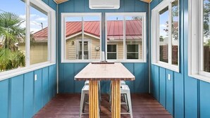 A covered patio with a wooden table and chairs, large windows, and a ceiling fan. - Great Views -Pet Friendly -Great Rates for Late Summer and Fall Dates -Book Now! (Mexico Beach)