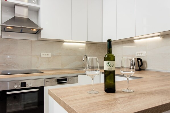 Una cocina moderna con horno empotrado, campana extractora de acero inoxidable y encimera de madera.
