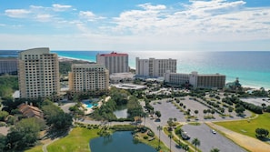 A high-rise hotel complex with multiple buildings, a swimming pool, and a view of the ocean.