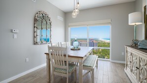 A dining area with a view of the ocean, a large mirror, and a table with chairs. - Gulf Views ~ Balcony ~ Full Kitchen ~ Resort Pool (Miramar Beach)