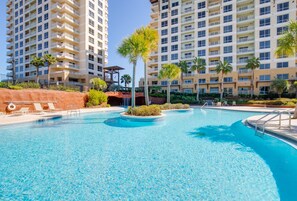 A swimming pool with lounge chairs and palm trees, surrounded by high-rise buildings.