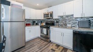 A modern kitchen with white cabinets, stainless steel appliances, and a patterned backsplash.