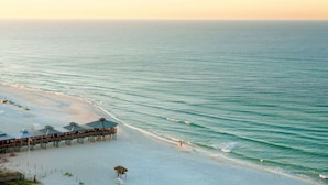 A beach with a pier, umbrellas, and a walkway.