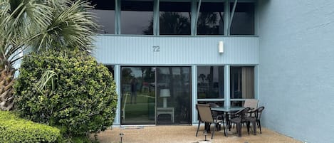 A modern building with a large glass entrance, numbered 72, and a patio area with outdoor seating.