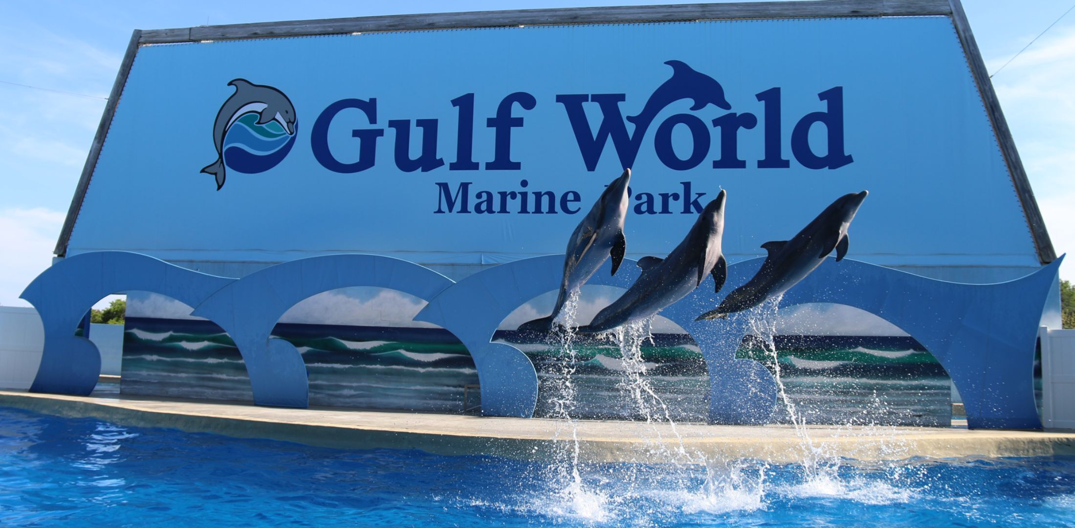 A sign with the text 'Gulf World Marine Park' and dolphins jumping out of the water.