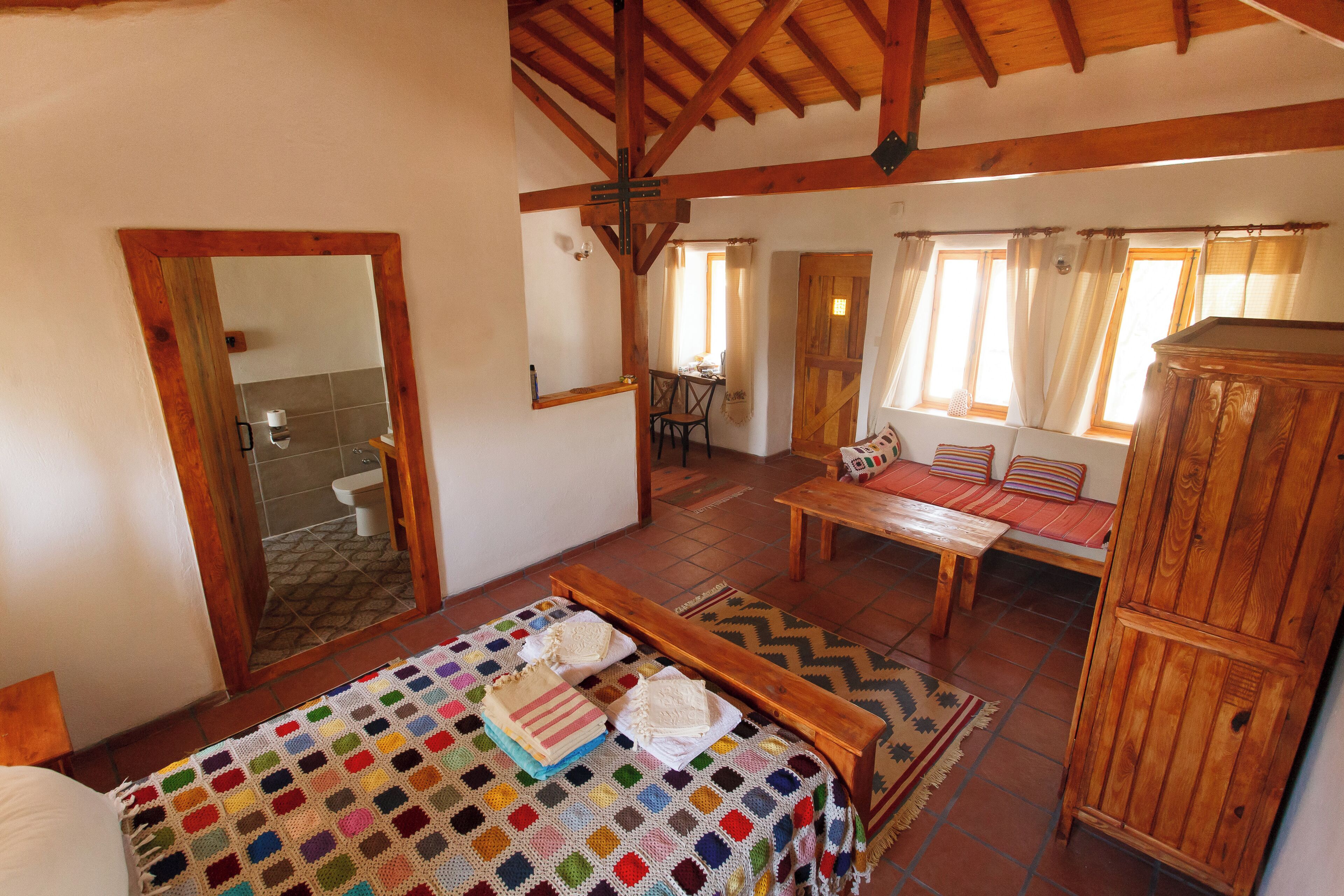 Una habitación acogedora con una cama, una mesa de madera y un banco.