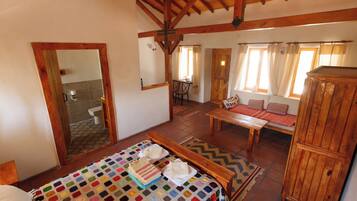 Una habitación acogedora con una cama, una mesa de madera y un banco.