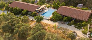 A villa with a swimming pool, surrounded by trees and a stone patio. - Ionia Guest House (Germencik)