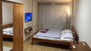 A bedroom with a bed, a TV mounted on the wall, a bedside table with a lamp, and a wardrobe. - Apartman Sever Hroncova (Kosice)